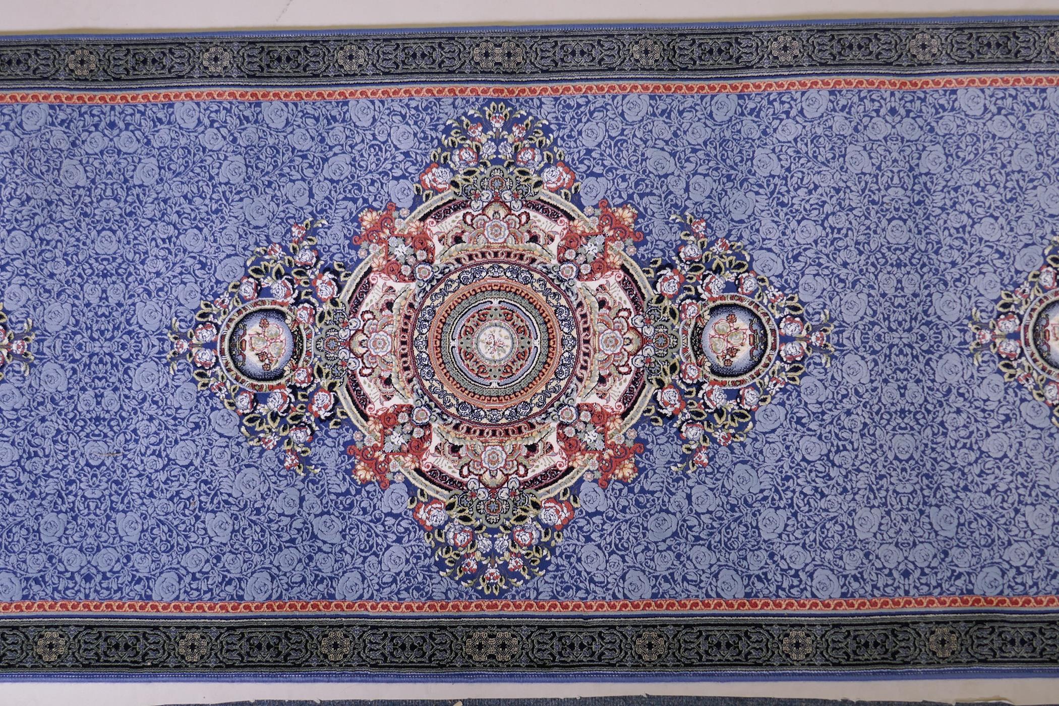 An Iranian fine woven blue ground runner with a medallion design surrounded by an embossed all