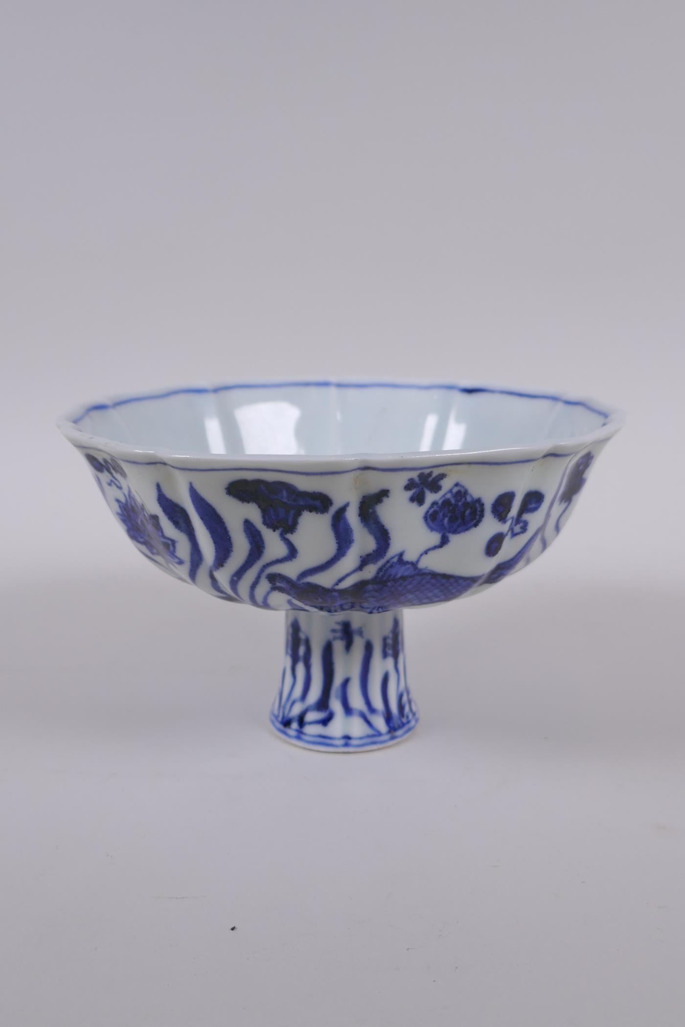 A blue and white porcelain stem bowl of lobed form, decorated with carp in a lotus pond, Chinese