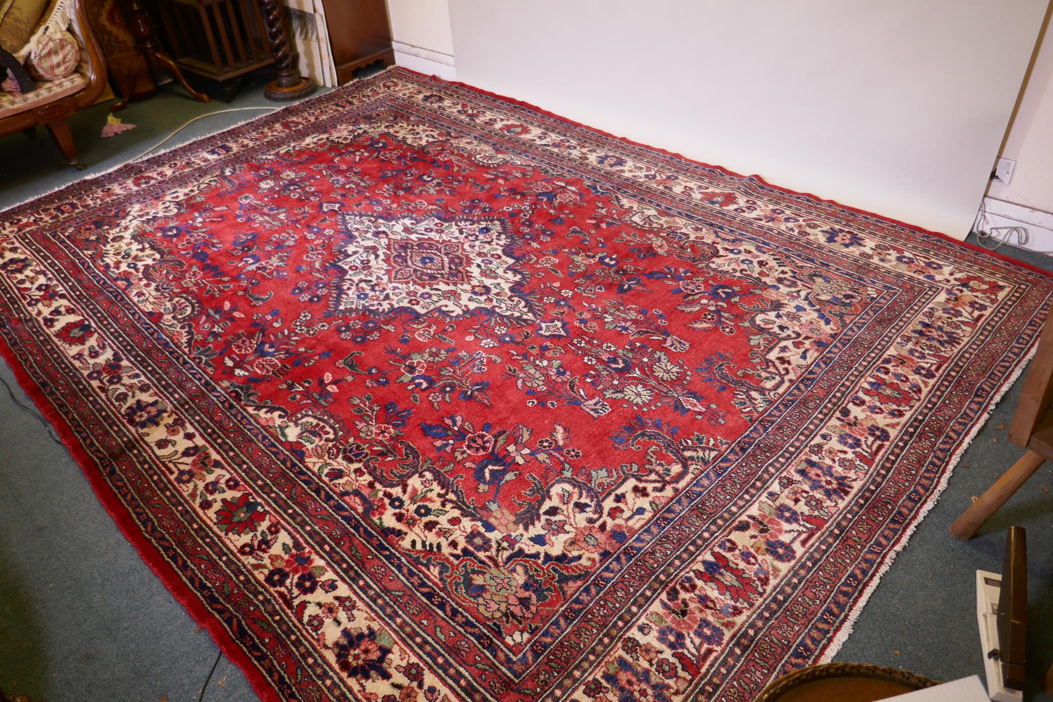 A Persian full pile red ground hand woven Sarouk village carpet with a floral medallion pattern - Image 2 of 6