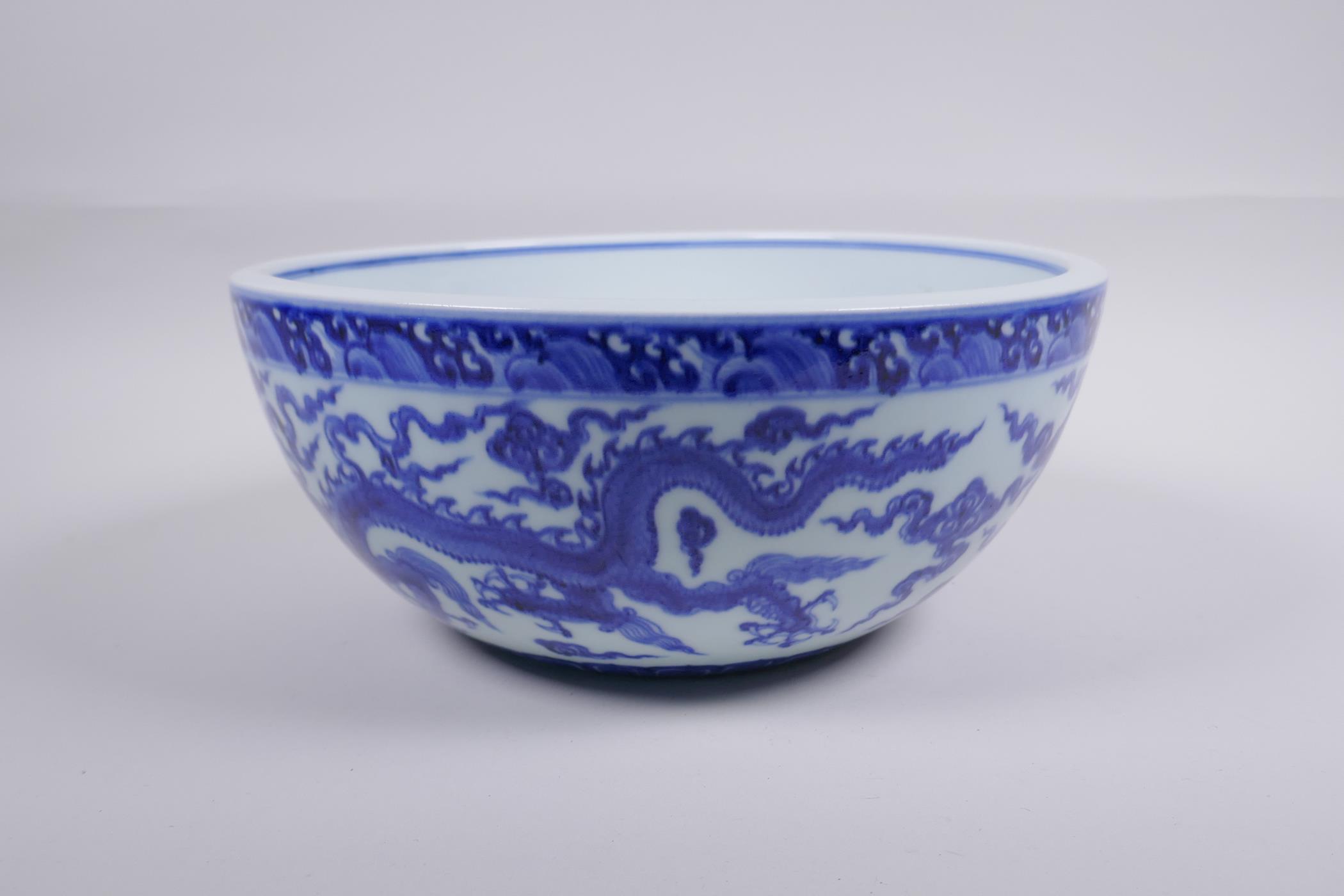 A blue and white porcelain bowl decorated with dragons in flight, Chinese Xuande 6 character mark to - Image 2 of 6