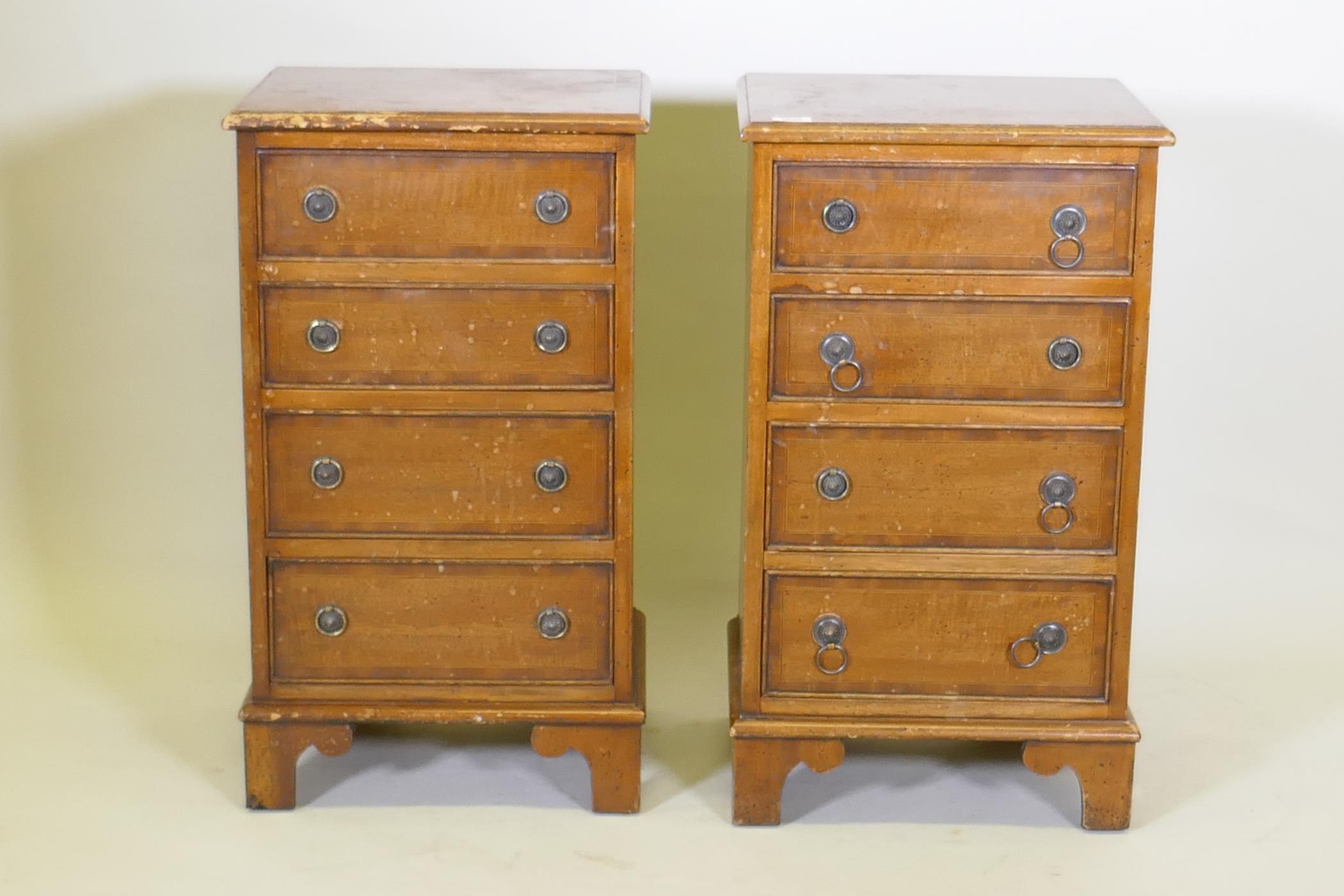 A pair of mahogany side chests of four graduated drawers with banded inlay, raised on bracket