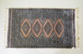A hand woven wool rug with geometric design on a faded brown field, 79 x 136cm