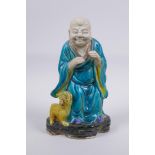 A Chinese polychrome porcelain figure of Lohan with a fo dg, AF, 21cm high