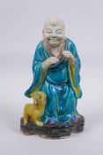 A Chinese polychrome porcelain figure of Lohan with a fo dg, AF, 21cm high