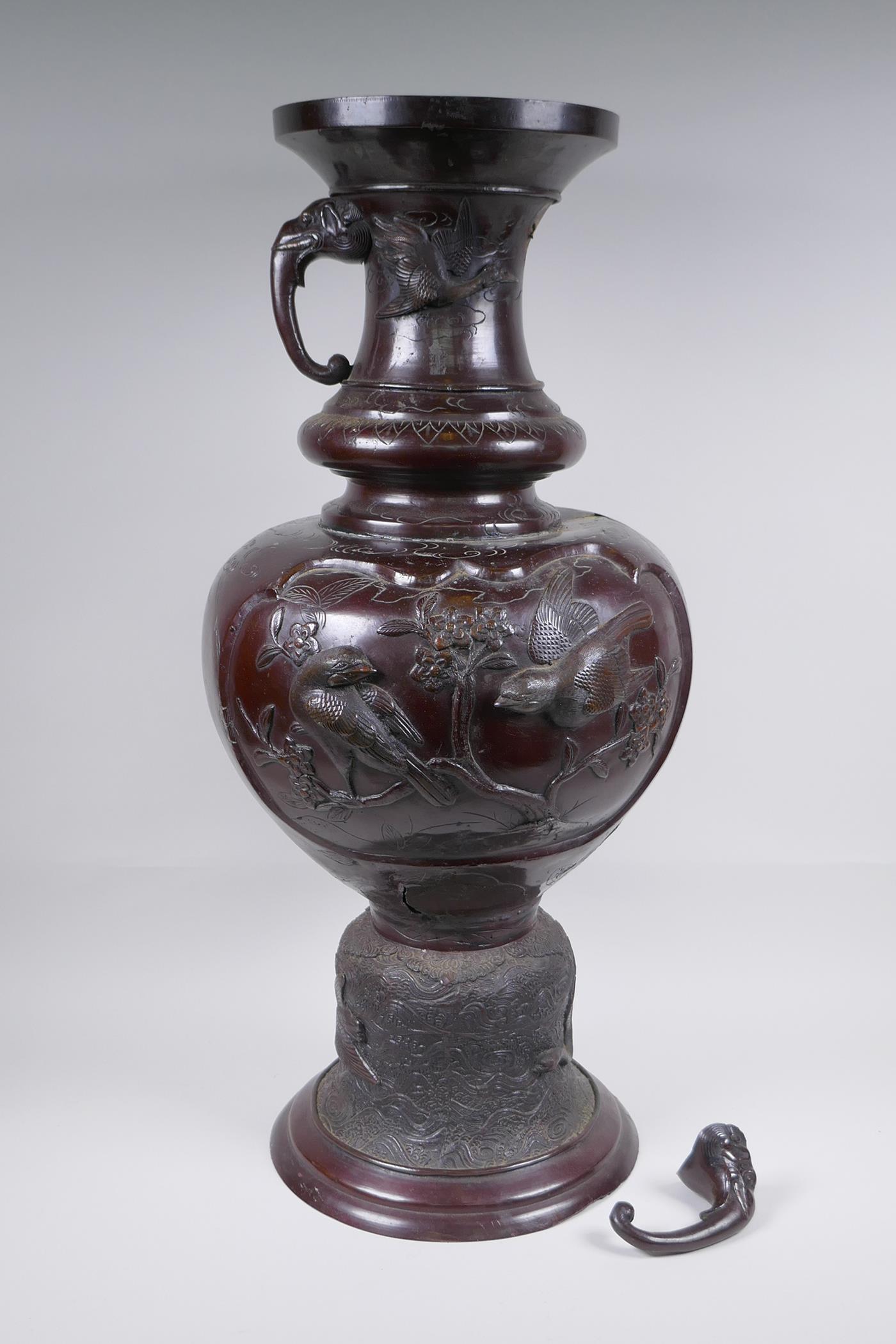 A Japanese Meiji period bronze urn with two handles and raised decorative panels depicting asiatic