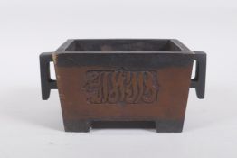 A Chinese bronze two handled censer with decorative script panels, impressed seal mark to base, 19 x