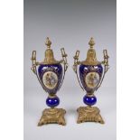 A pair of ormolu and Sevres style porcelain urns with two handles and decorative panels depicting