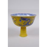 A Chinese yellow ground porcelain stem bowl with blue and white dragon decoration, 10cm high x