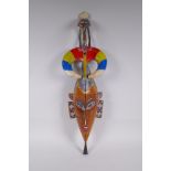 An African carved and brightly painted wood wall mask with a wading bird surmount, 67cm long
