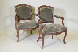 A pair of early C19th French walnut open arm chairs with carved crests and arms, serpentine front,