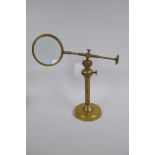 An adjustable brass table top magnifying glass, 24 cm high collapsed