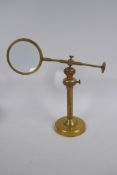 An adjustable brass table top magnifying glass, 24 cm high collapsed