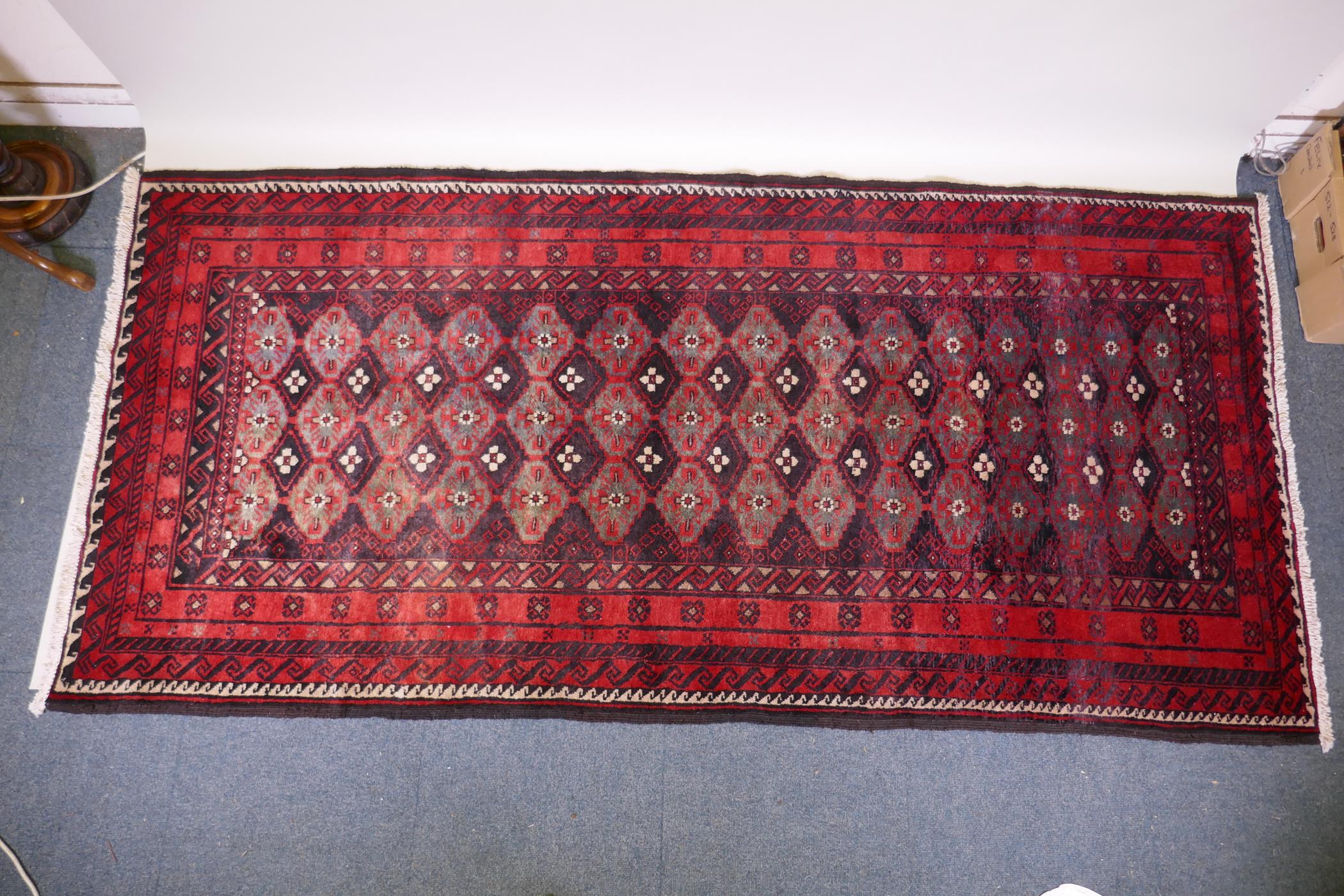 A full pile hand woven red ground carpet with a geometric floral design, 268 x 130cm