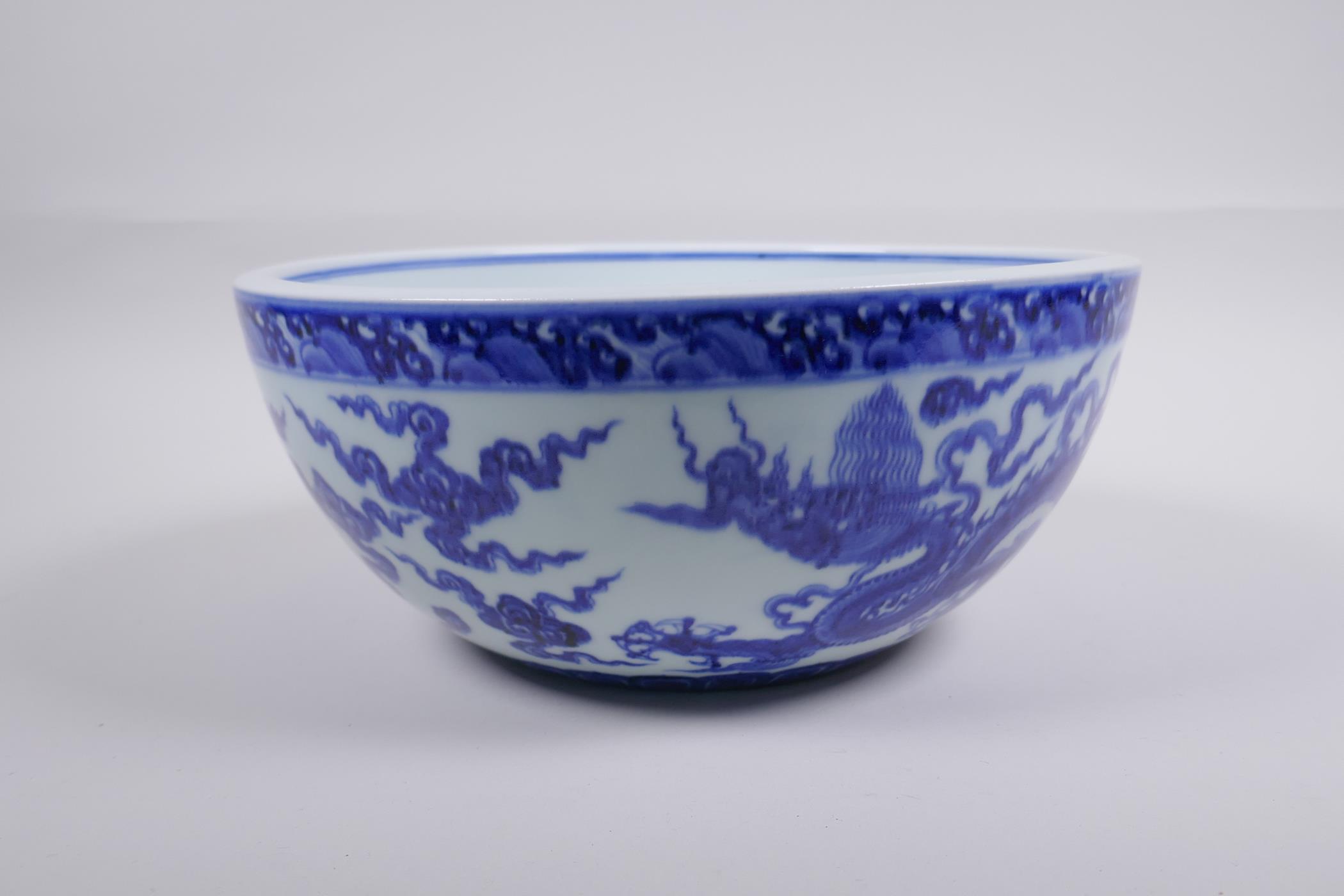 A blue and white porcelain bowl decorated with dragons in flight, Chinese Xuande 6 character mark to - Image 3 of 6