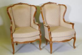 A pair of Louis XV style walnut wingback arm chairs with carved detail