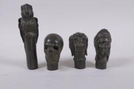 Four bronze walking stick handles in the form of a skull, dog head, head bust and a parrot,