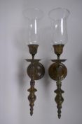 A pair of patinated bronze wall sconces with glass shades, 56cm long