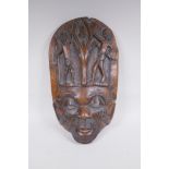 An antique African carved hardwood wall mask with figural and antelope decoration, 28 x 47cm