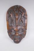 An antique African carved hardwood wall mask with figural and antelope decoration, 28 x 47cm