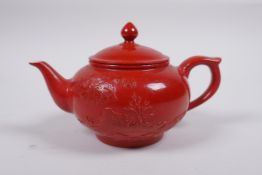 A Chinese iron red glazed porcelain teapot with raised landscape scene decoration, incised
