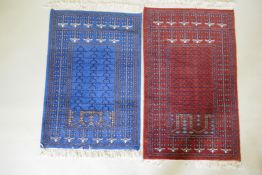 An oriental hand woven wool prayer rug with geometric designs on a red field and another in blue,