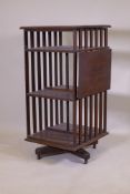 A Victorian oak revolving bookcase, three tiered with a ratcheted drop flap, raised on an iron base,
