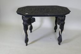A C19th Ceylonese lacquered hardwood side table, the shaped top profusely carved with a procession