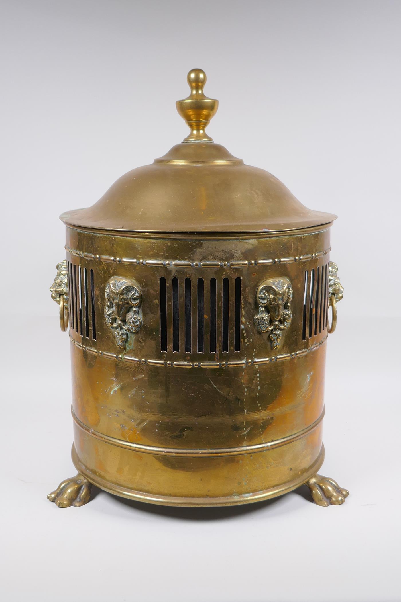 An antique brass coal scuttle with two lion mask loop handles, rams mask decoration and pawed