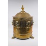 An antique brass coal scuttle with two lion mask loop handles, rams mask decoration and pawed