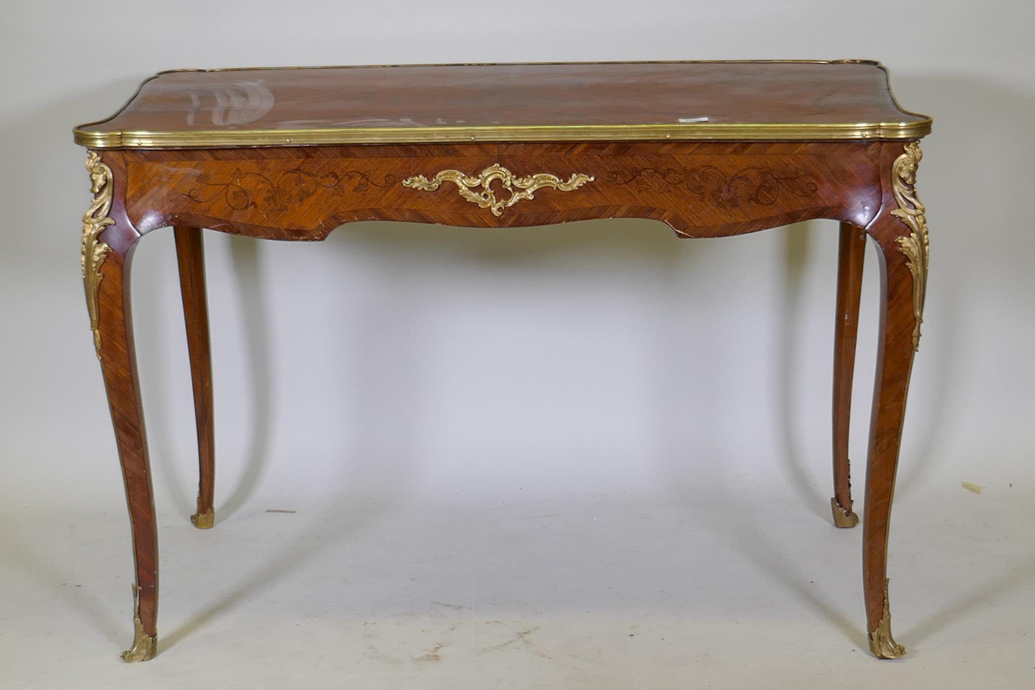 A French marquetry inlaid bureau plat, with shaped top, single drawer and ormolu mounts, bears label