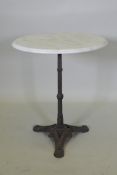 A marble topped bistro table with a cast iron base, 73cm high x 61cm diameter