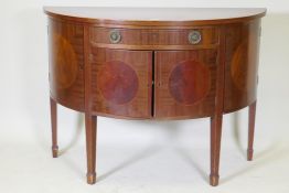 A C19th figured mahogany demi lune commode with two cupboards flanking a single drawer over two