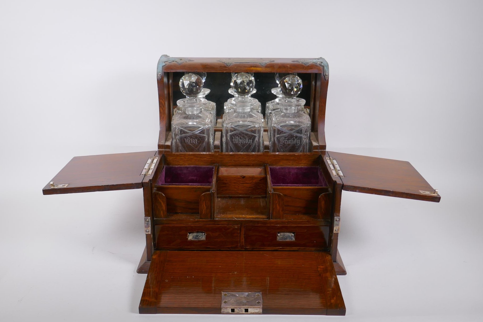 A Victorian oak and silver plated three bottle tantalus, opening to reveal fitted compartments,