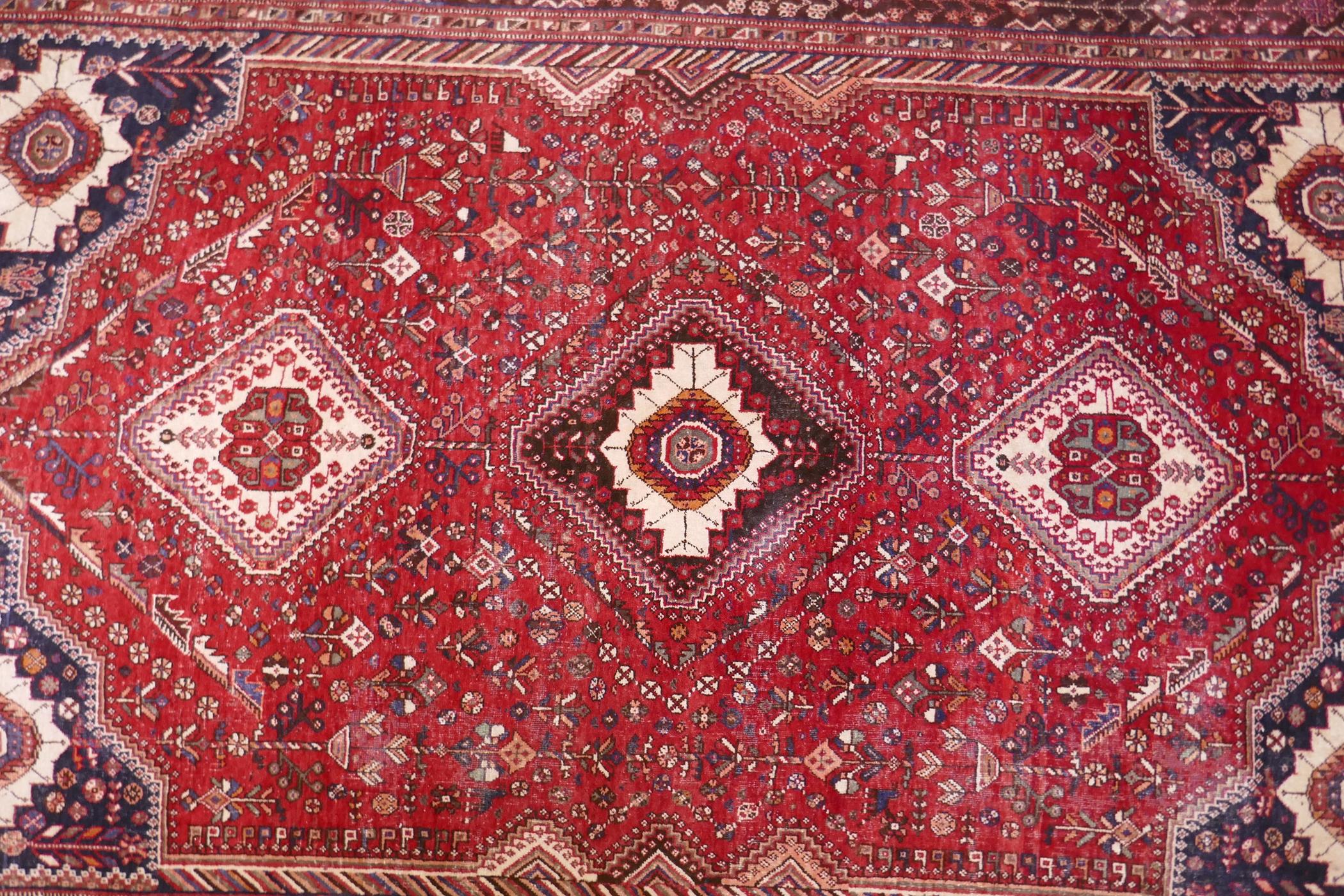 A hand woven red ground Persian carpet with a unique medallion design and chocolate brown borders, - Image 2 of 5