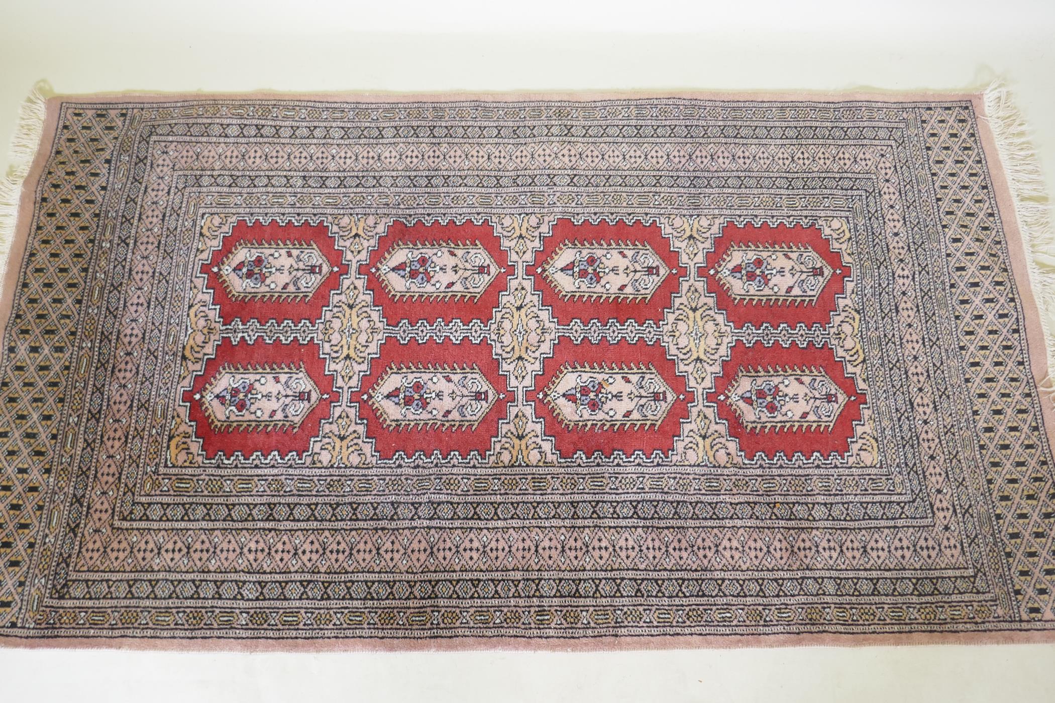 A hand woven wool Bokhara rug, medallion design on a pink ground, 94 x 150cm - Image 2 of 3