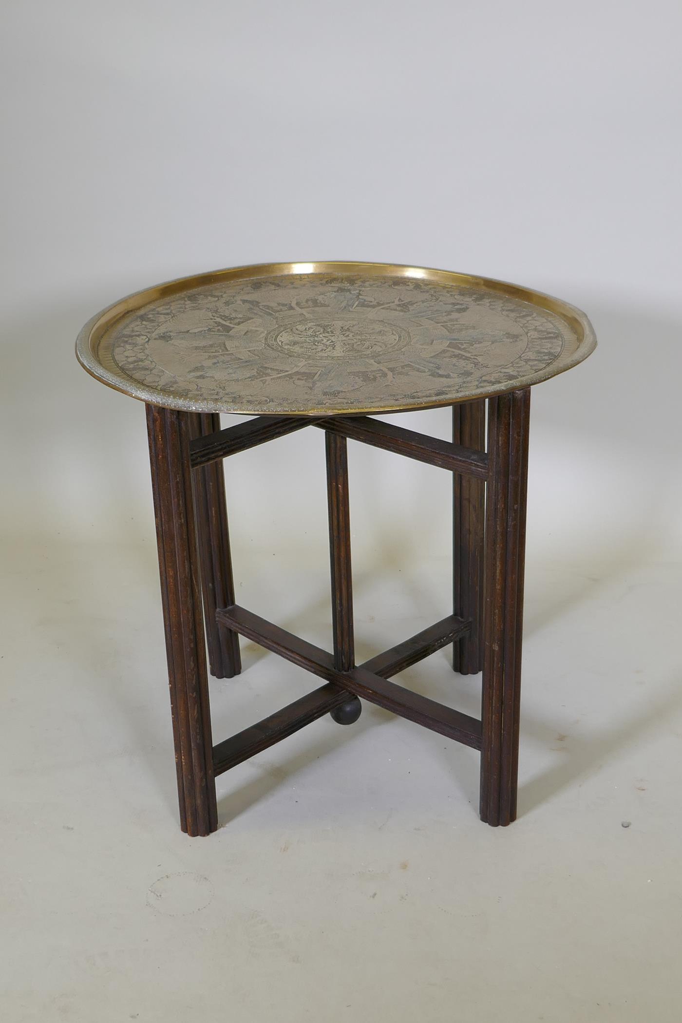 A Victorian brass top table with Japanese inspired decoration, on a folding wood base, 59 dia. x