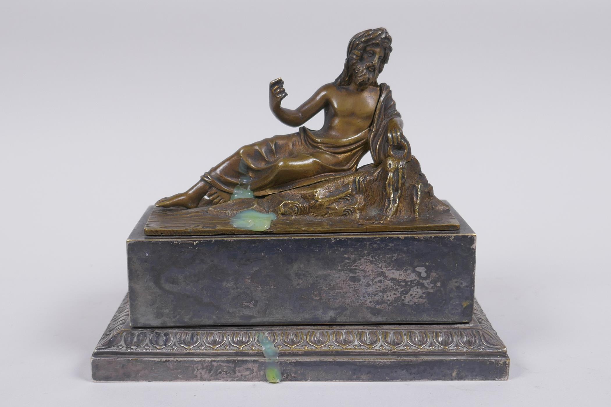 A Grand Tour silver plated ink well with bronze mount in the form of a reclining Greco-Roman figure,