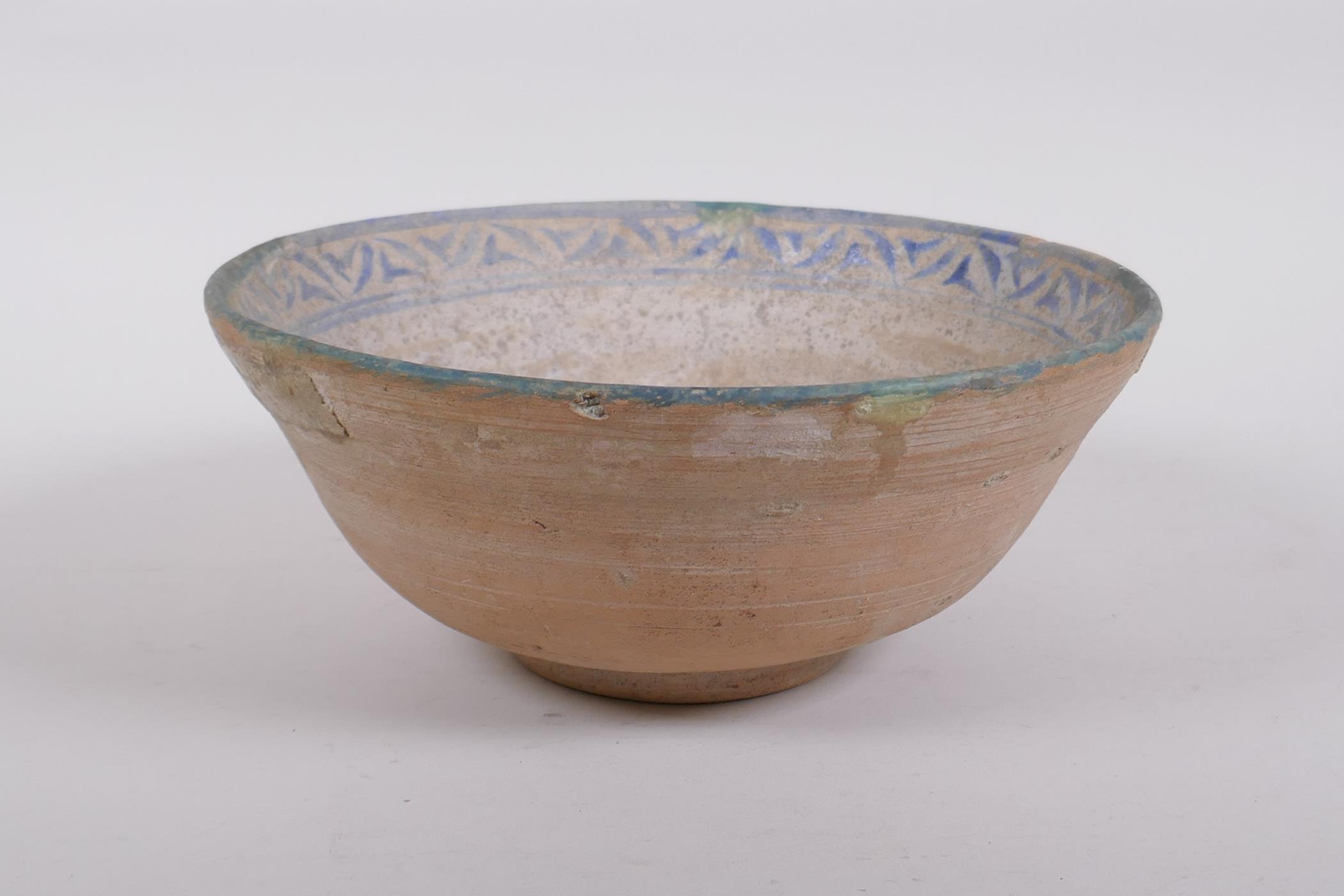 A middle eastern terracotta bowl with blue and white glazed decoration to the interior, 20cm
