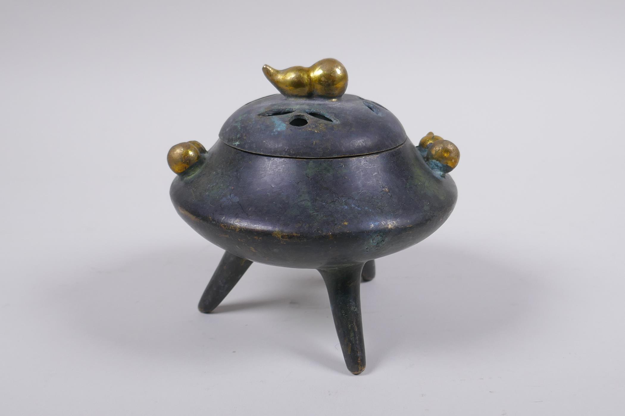 A Chinese bronze censer and cover on tripod supports with gilt gourd handles and knop impressed seal