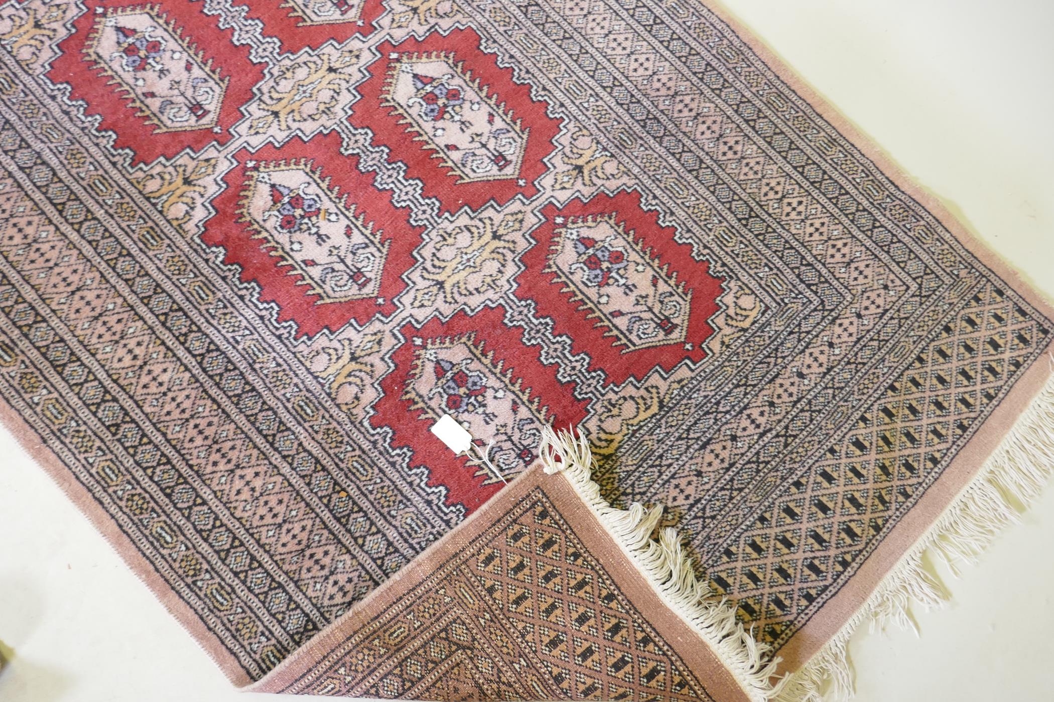 A hand woven wool Bokhara rug, medallion design on a pink ground, 94 x 150cm - Image 3 of 3