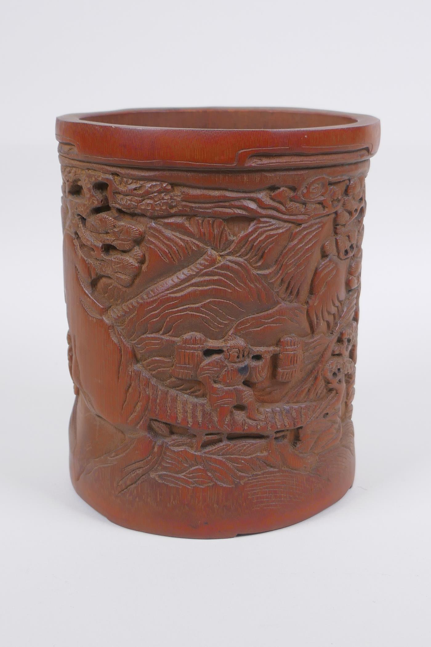 A Chinese carved bamboo brush pot decorated with figures in a landscape, 16cm high