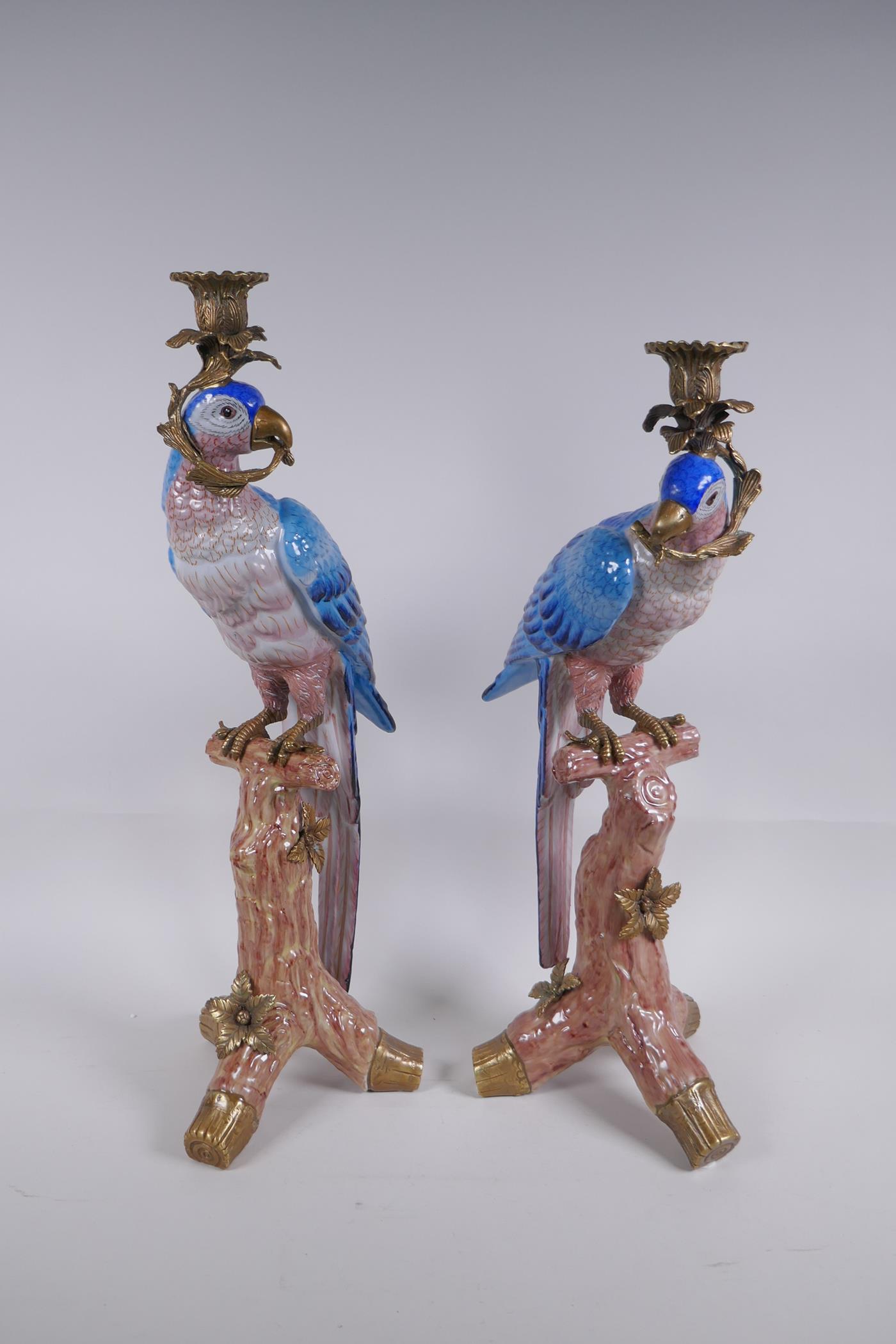 A pair of polychrome porcelain and gilt metal mounted parrot candlesticks, 52cm high