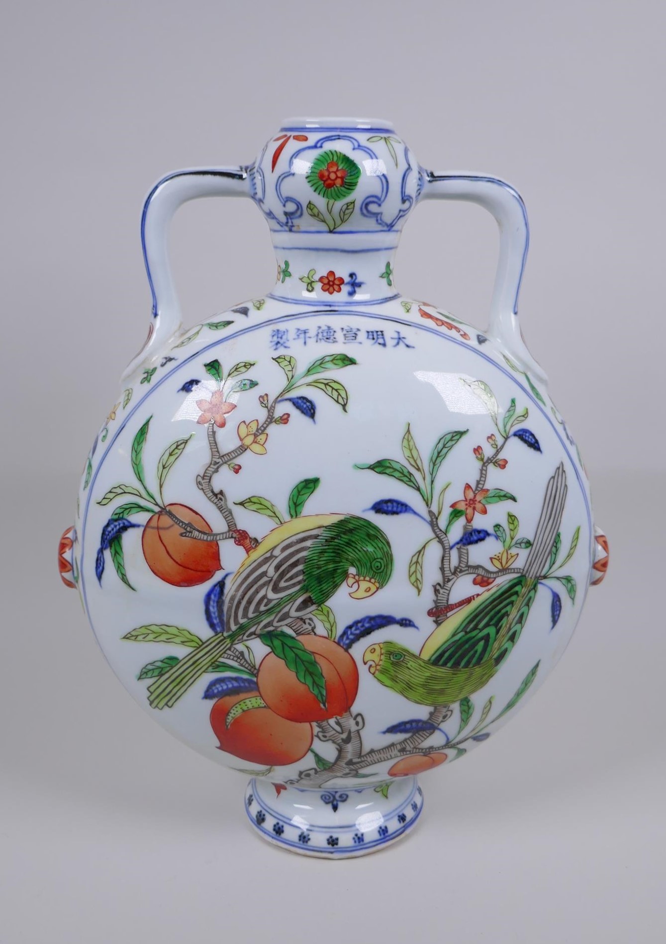 A Chinese polychrome porcelain two handled moon flask decorated with parrots in a peach tree, Xuande