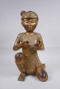 A Tibetan carved gilt and painted wood figure of a musician with inset glass decoration, 38cm