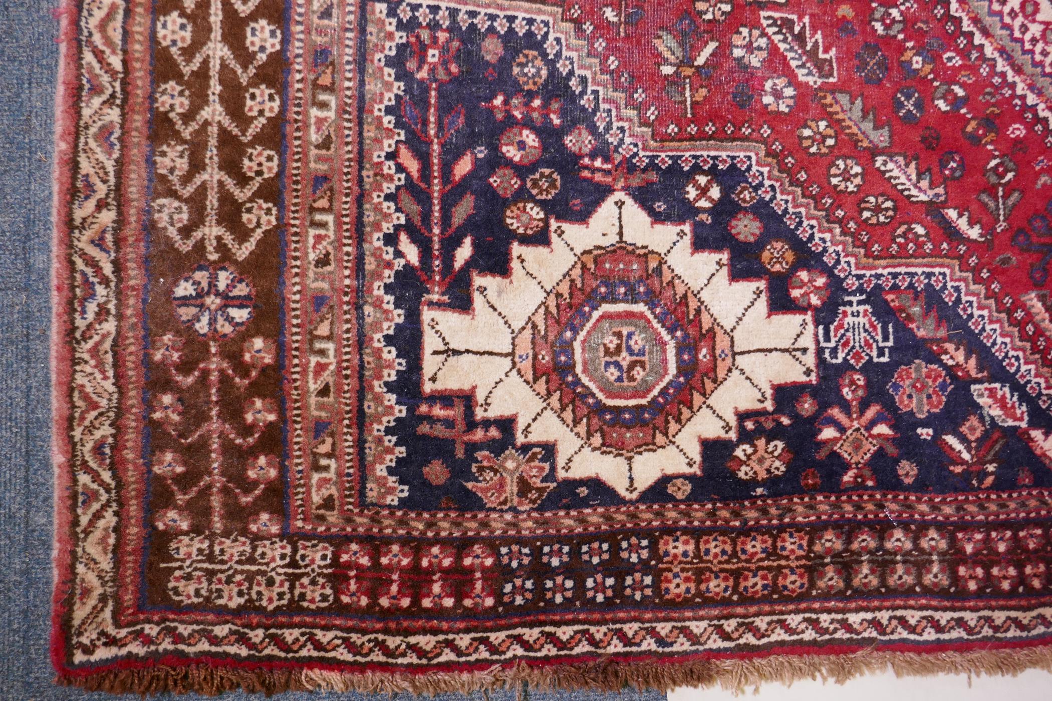 A hand woven red ground Persian carpet with a unique medallion design and chocolate brown borders, - Image 4 of 5