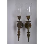 A pair of patinated bronze wall sconces with glass shades, 56cm long