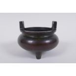 A Chinese bronze two handled censer raised on tripod supports, 9cm high x 10cm diameter