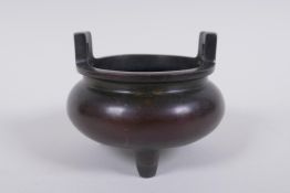 A Chinese bronze two handled censer raised on tripod supports, 9cm high x 10cm diameter