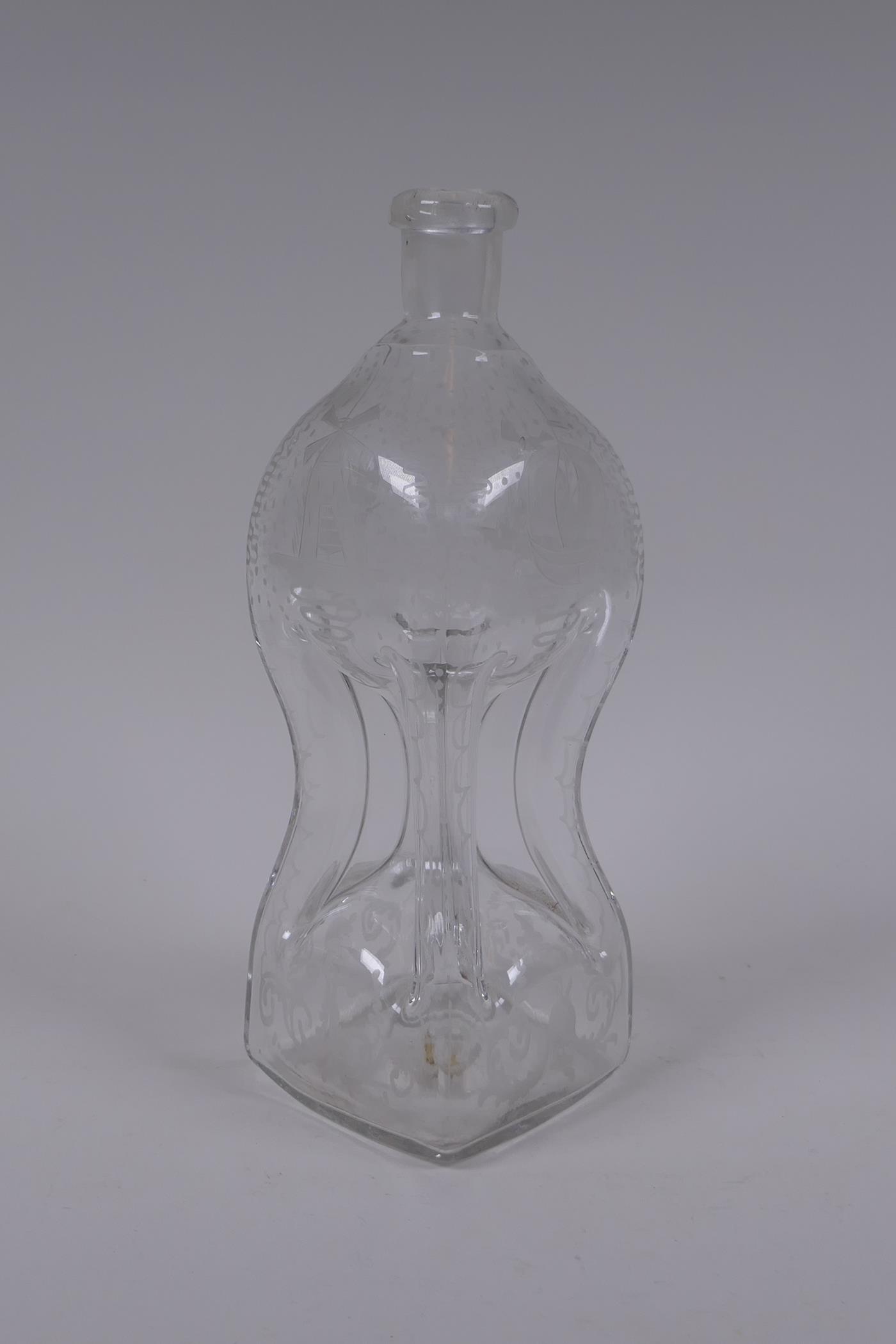 An antique glass bottle of pinched waist form and etched decoration, 28cm high