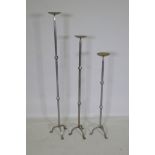 Three graduated wrought metal pricket candlesticks, largest 113cm